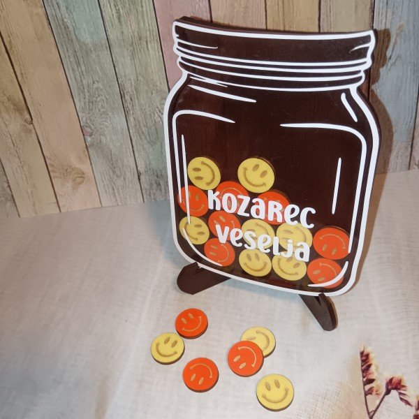 Kozarec veselja z žetoni v obliki krogcev z nasmeški, motivacijski pripomoček